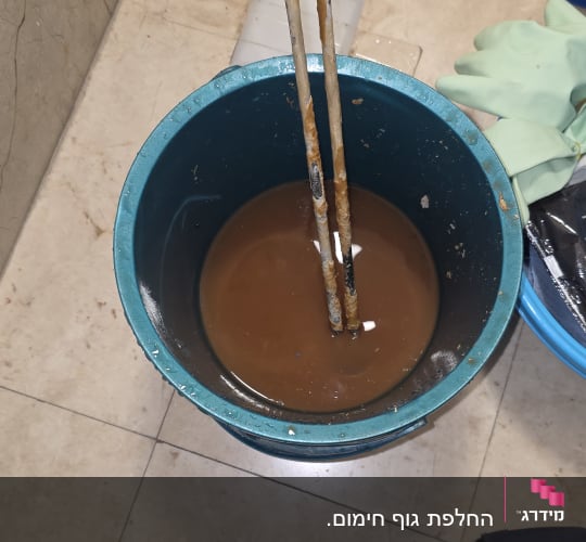 דלי עם מים חלודים וכלי עבודה בתחום הדוד שמש